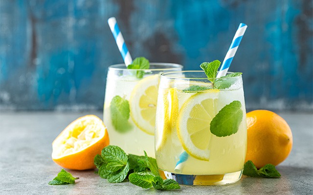 Zwei Gläser Limonade mit Zitronenscheiben, Minze und Trinkhalmen.