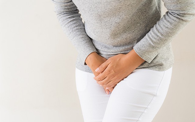 Eine Person hält sich den Bauch, als hätte sie Schmerzen.