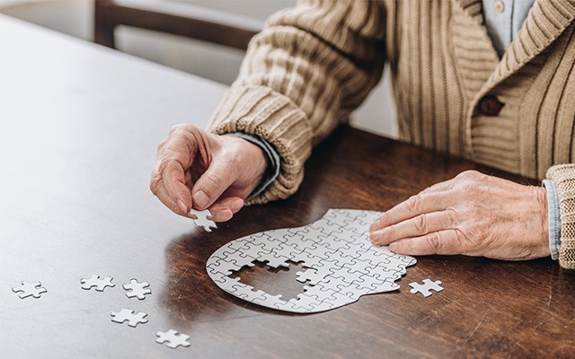 Ältere Person legt ein Puzzle in Form eines Kopfes
