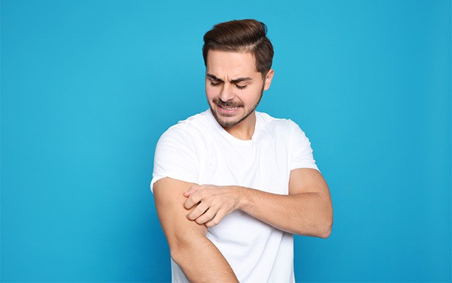 Ein Mann kratzt sich am Arm und schaut besorgt.