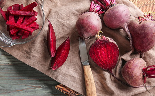 Rote Bete mit Messer, geschnitten und ganz, auf einem Tuch.