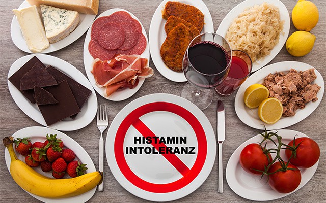 Verschiedene Lebensmittel mit einem Schild "Histaminintoleranz" in der Mitte.