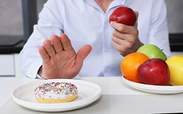 Ein Mann wählt einen Apfel statt eines Donuts.