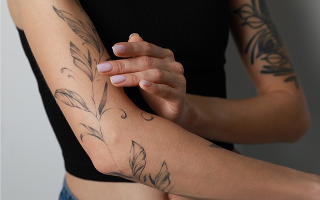 Ein Arm mit Blumen-Tattoos wird von einer Hand berührt.