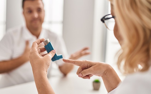 Zwei Personen besprechen einen blauen Inhalator.