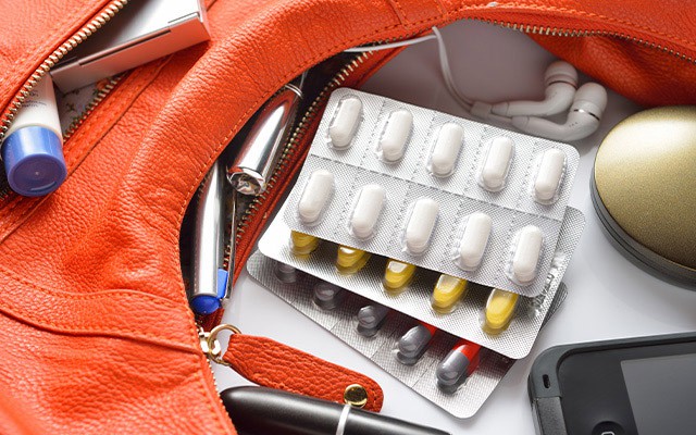 In der Tasche liegen Tabletten, Kopfhörer und ein Handy.