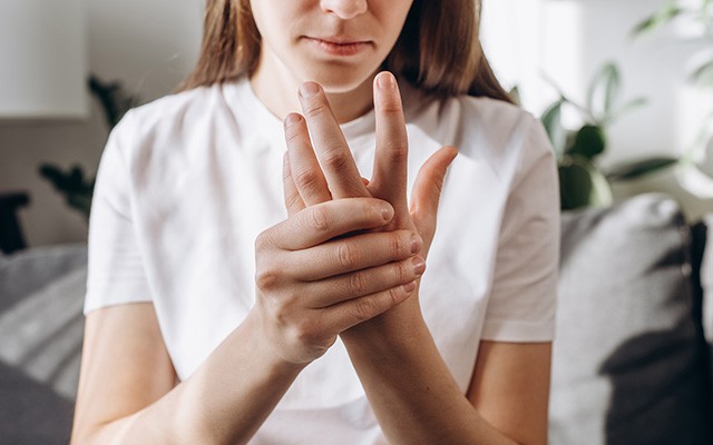 Eine Person reibt ihre schmerzenden Finger.
