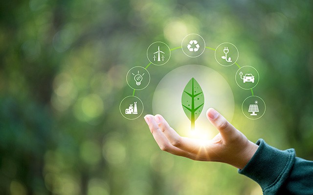 Eine Hand hält ein leuchtendes Blatt mit Symbolen für erneuerbare Energie.