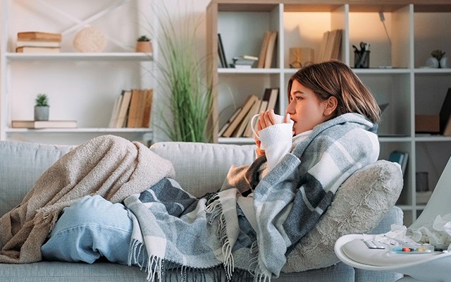 Frau krank auf dem Sofa mit Tee