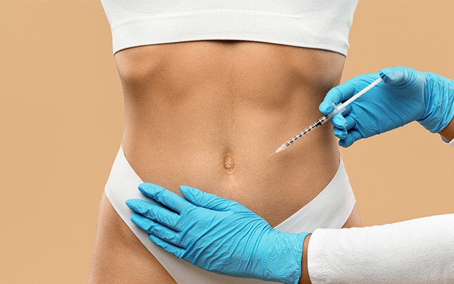 Eine Person erhält eine Injektion in den Bauch von jemandem mit blauen Handschuhen.