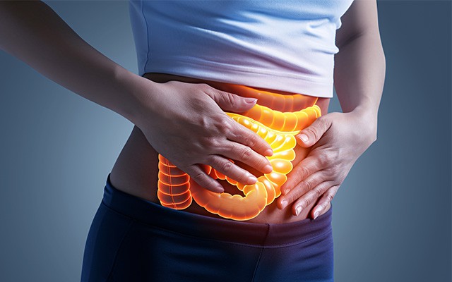 Eine Person hält ihren Bauch, der leuchtende Darm ist sichtbar.