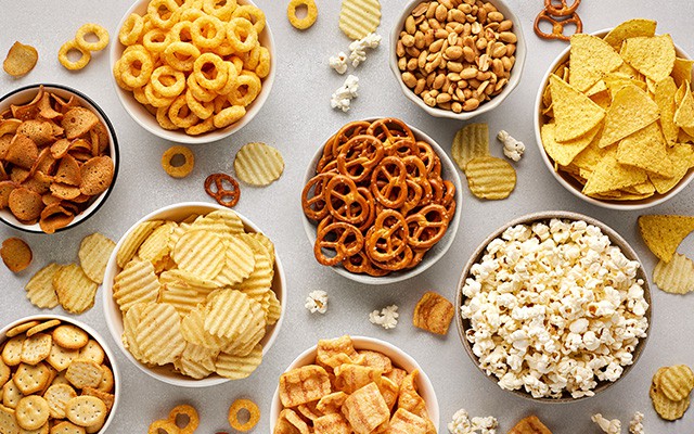 Verschiedene Snacks und Chips sind in Schüsseln auf einem Tisch verteilt.